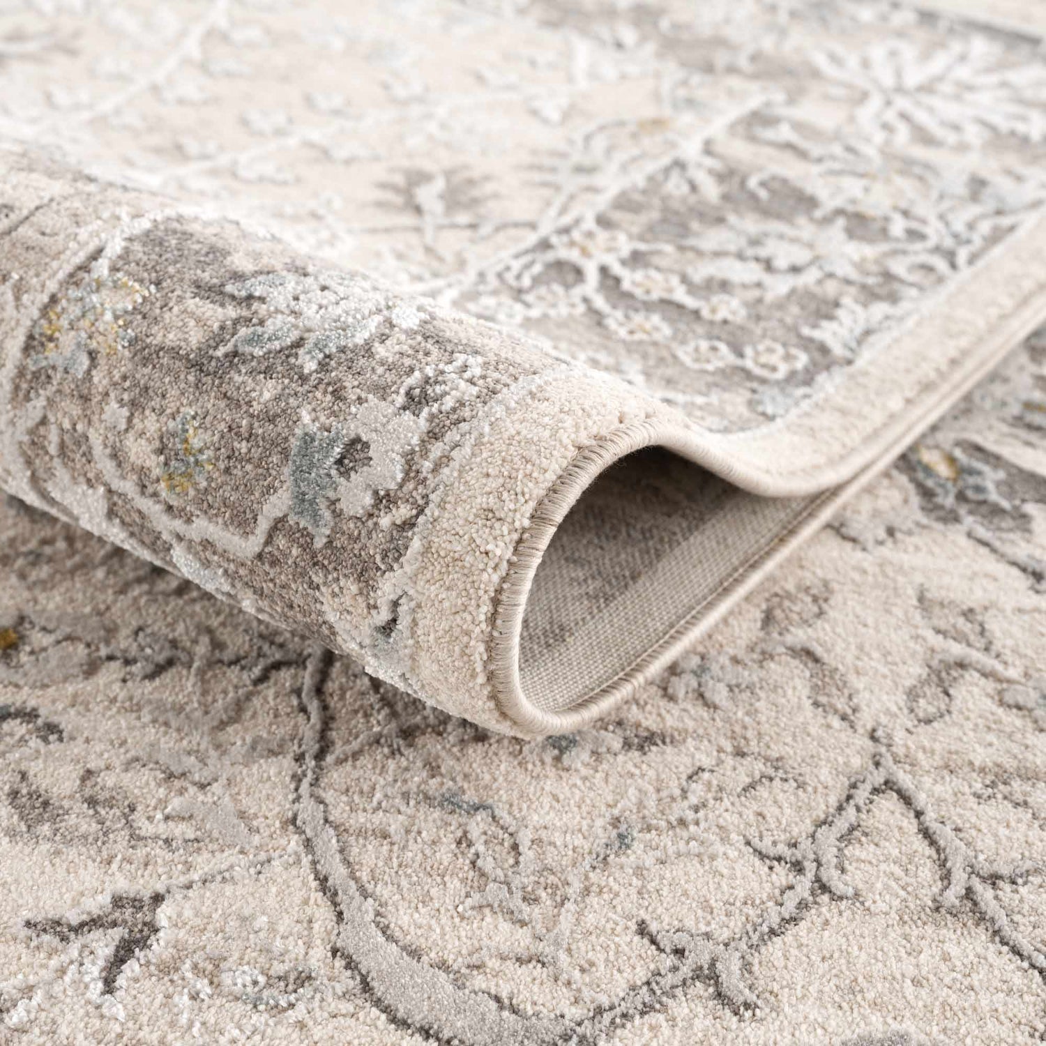 Close-up of the Gauge Cream & Gray Blue Rug showing its texture, neutral colors, and traditional pattern. Fold