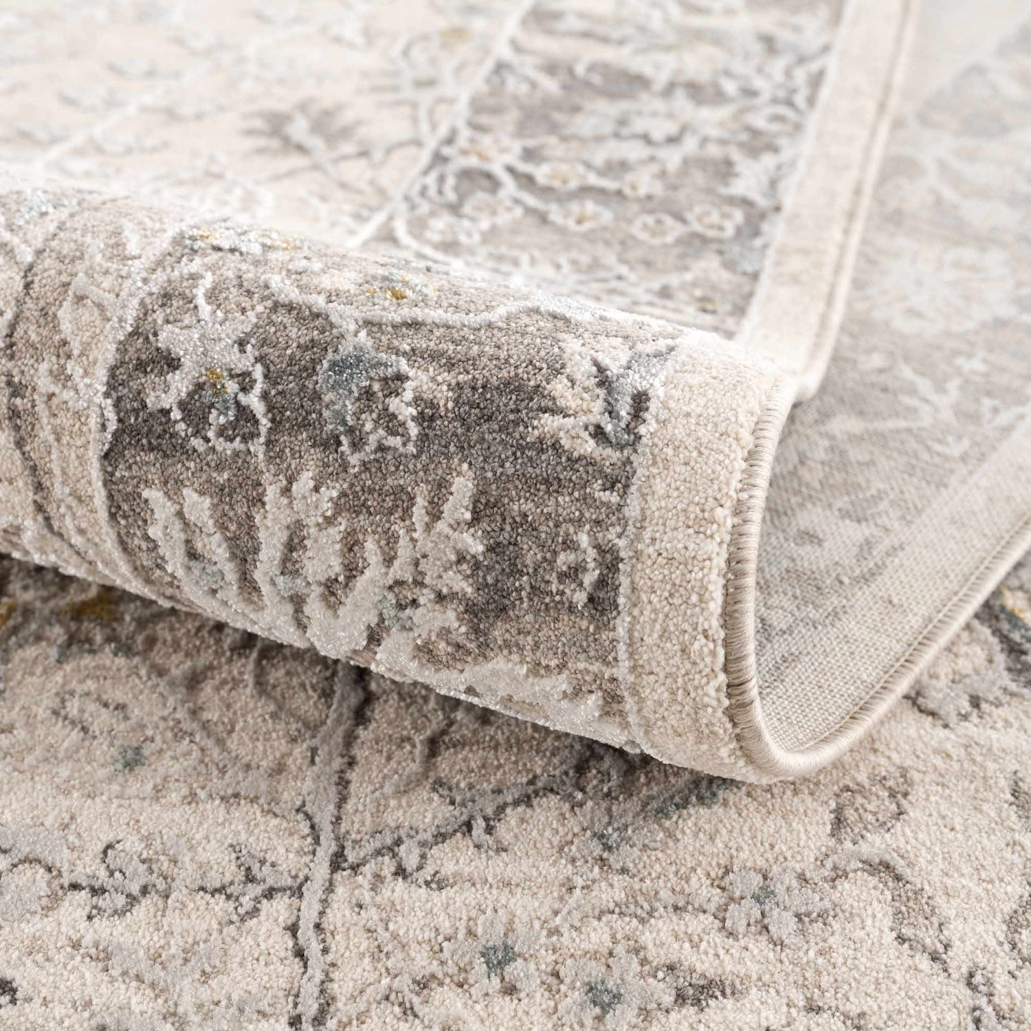 Close-up of the Gauge Cream & Gray Blue Rug showing its traditional pattern and soft, textured weave. Fold