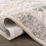 Close-up of the Gauge Cream & Gray Blue Rug showing its traditional floral pattern and soft, textured weave. Fold