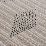 Close-up of the Lexi Area Rug showing beige and ivory stripes with a geometric black dotted pattern. Texture