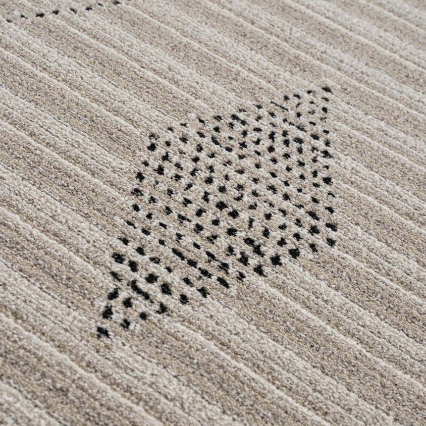 Close-up of the Lexi Area Rug showing beige and ivory stripes with a geometric black dotted pattern. Texture
