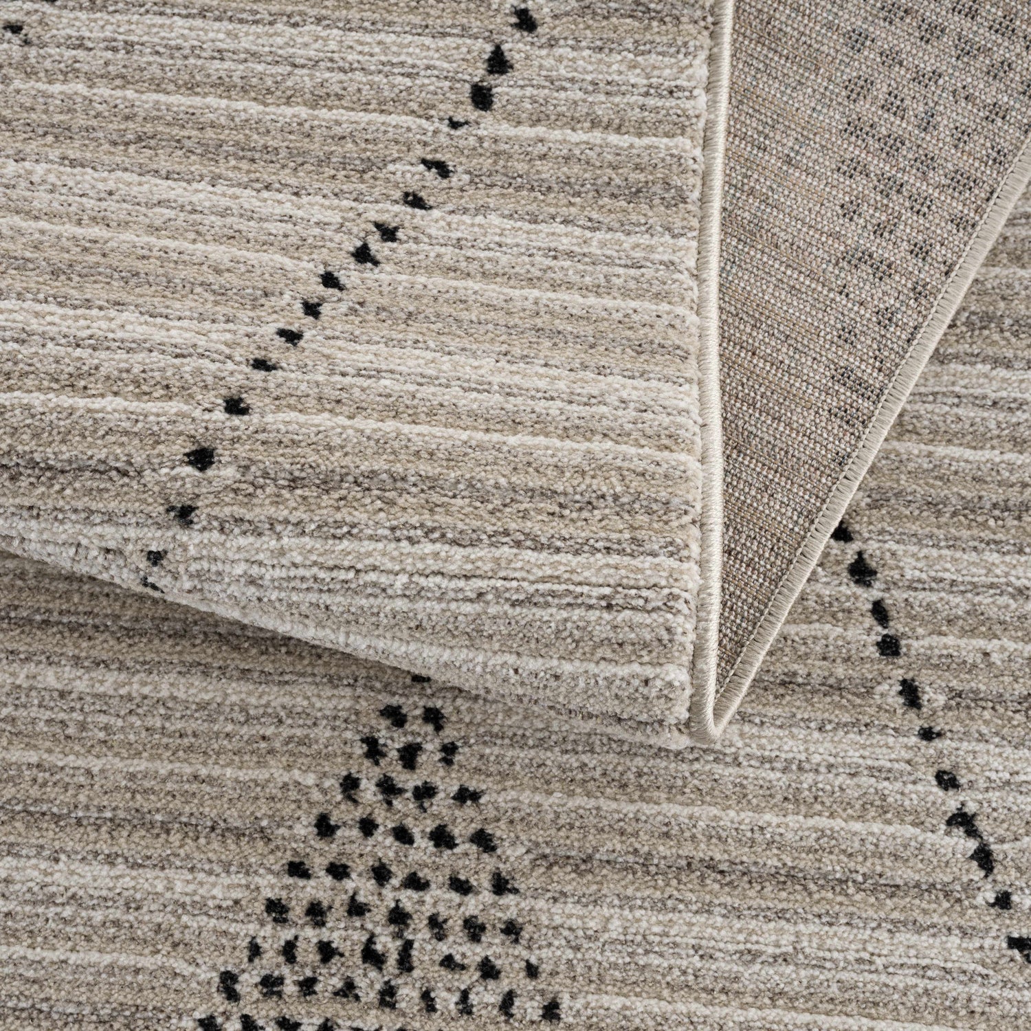 Close up of the beige Lexi Area Rug showing the geometric pattern and soft texture. Fold