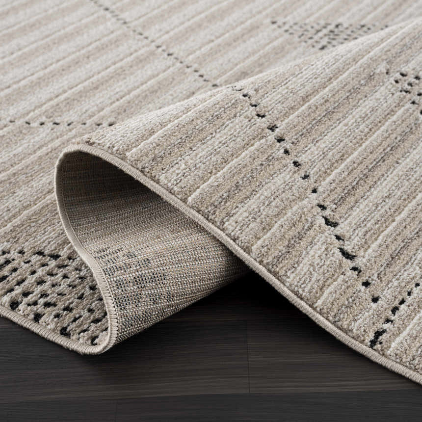 Close-up of the Lexi Area Rug, a beige and ivory geometric rug made of polyester, rolled up to show texture. Fold