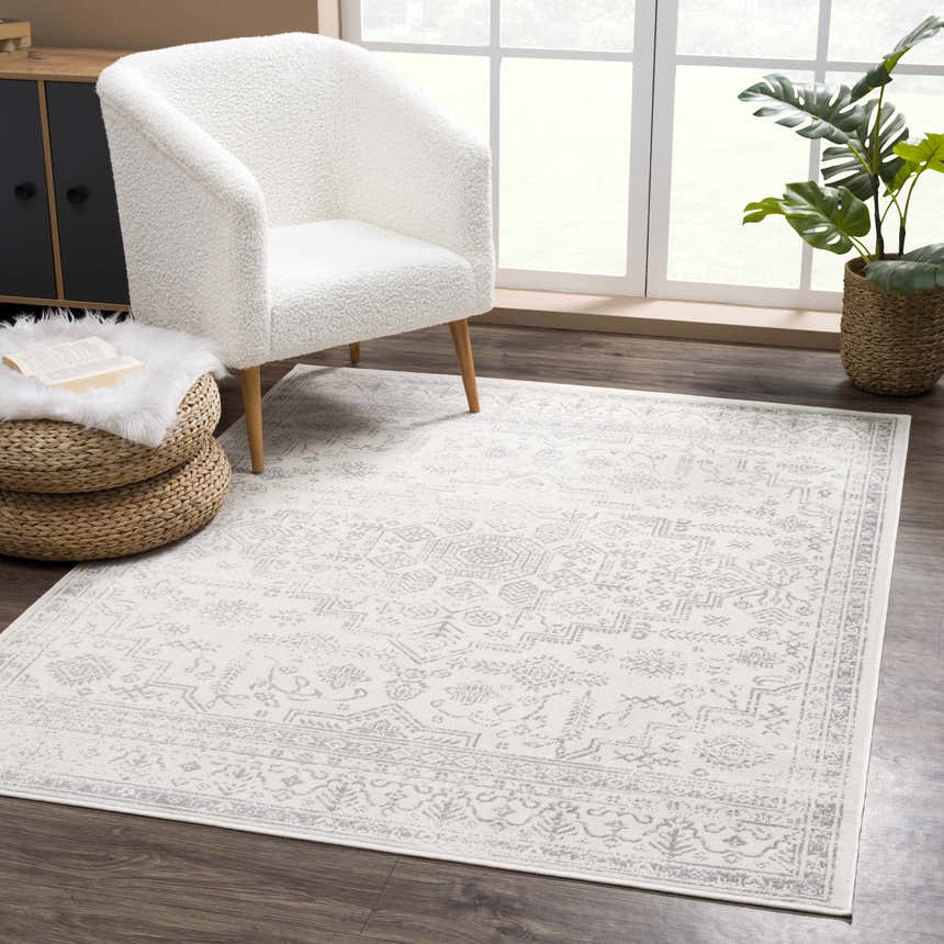 Cozy reading nook with Tigried Ivory & Gray area rug, white sherpa chair, woven ottoman, and indoor plant near window. Roomscene-Rectangle