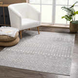 Living room scene with a Tigrican Light Gray 2334 Area Rug, white chair, woven ottoman, and wood floors. Contemporary style. Roomscene-Rectangle