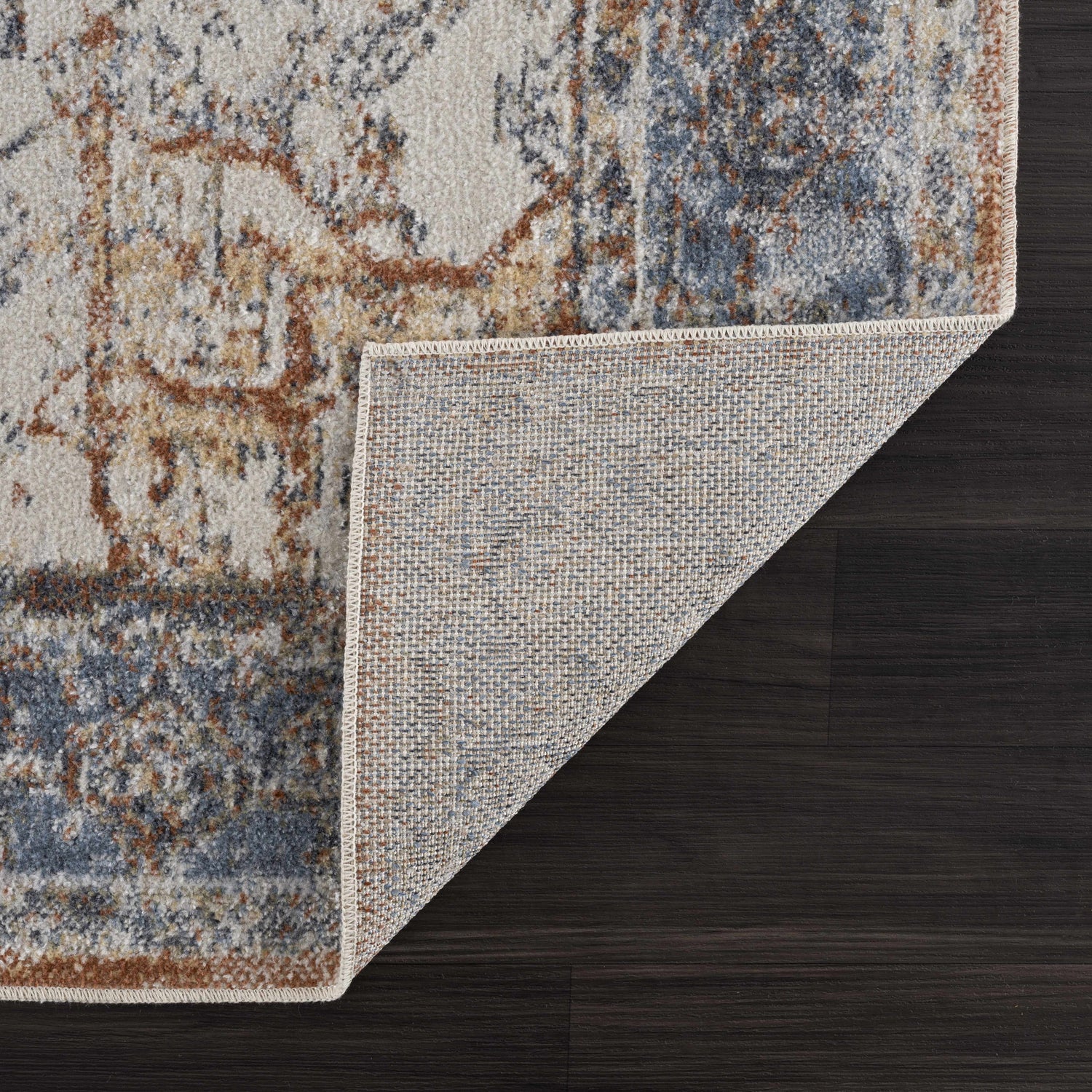 Close-up of the Blue Orange Hera Washable rug showing the traditional vintage pattern and the rug's underside texture. Fold