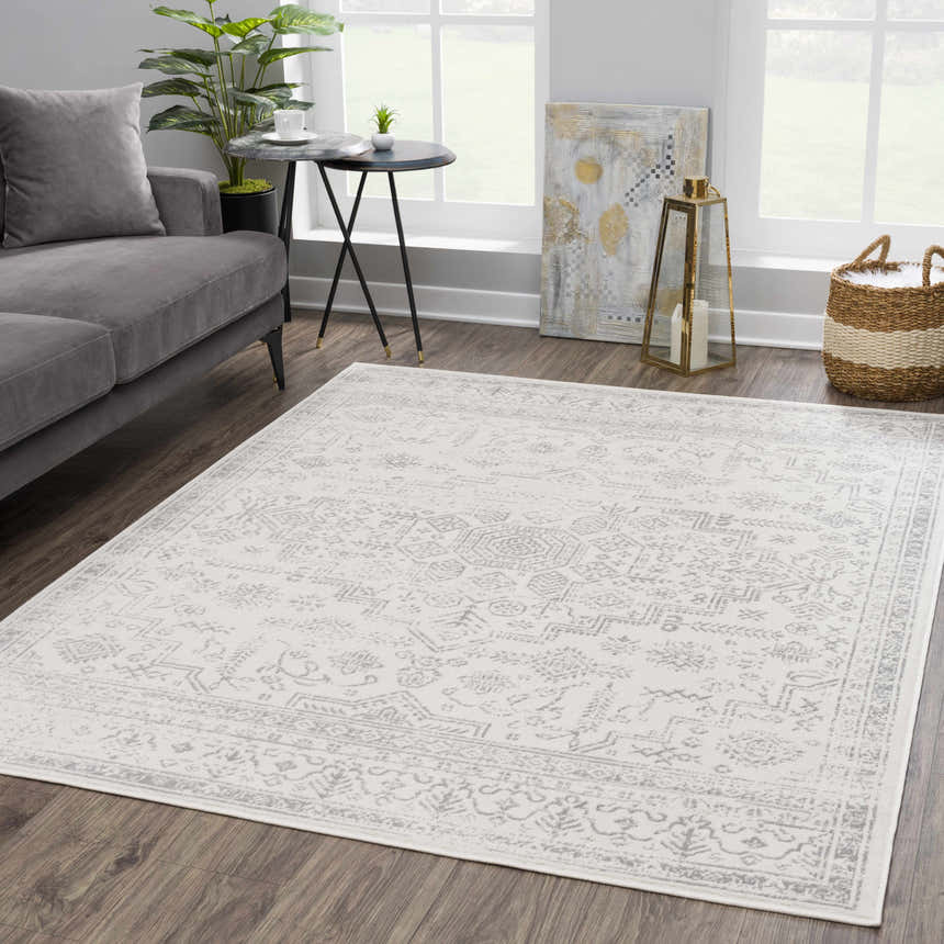 Living room scene with a Tigried Ivory & Gray 2323 Area Rug, gray sofa, side table, and natural light from a large window. Roomscene-Rectangle