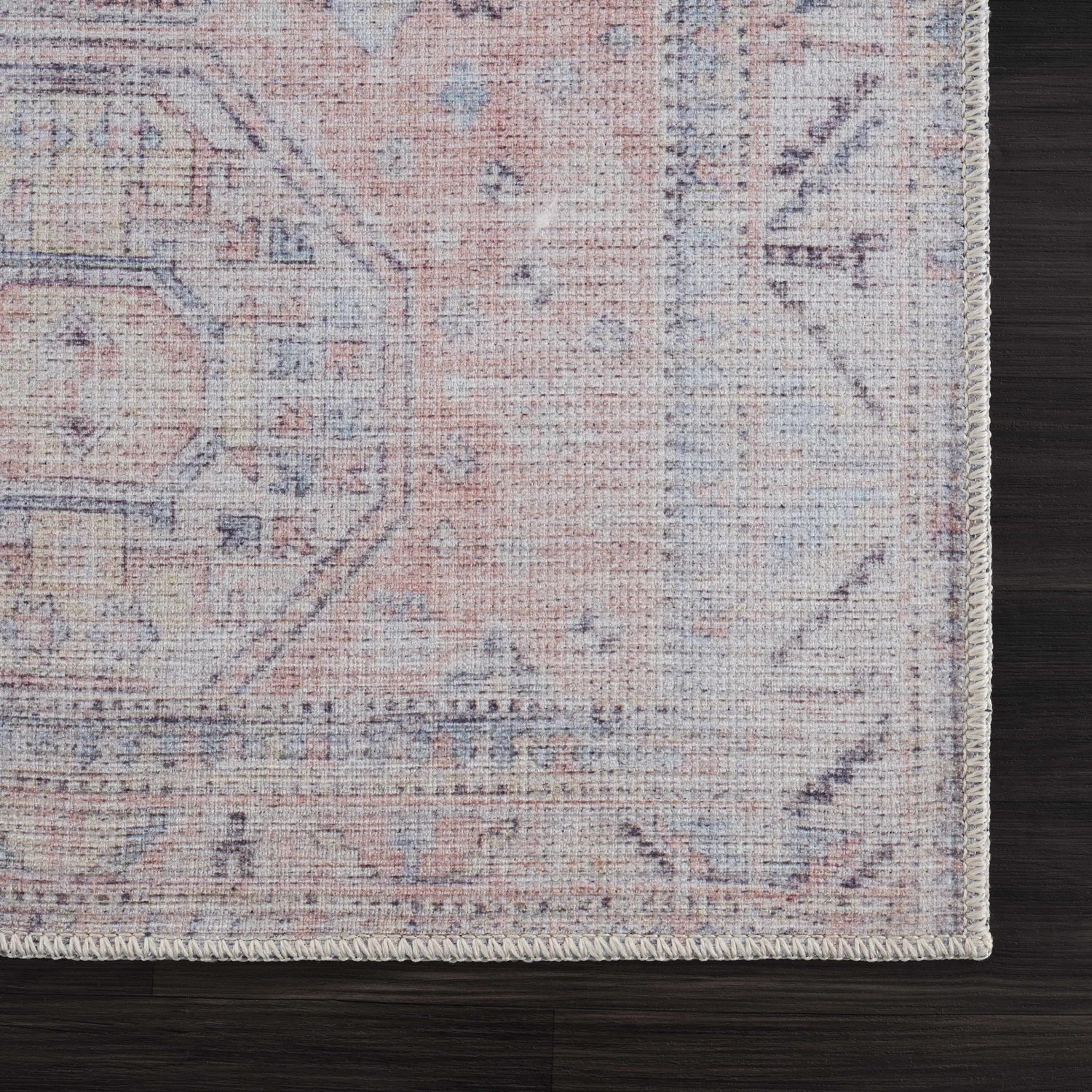 Close-up of the Morcott Peach Washable Area Rug showing its traditional, oriental-inspired design and soft peach, blue, and ivory colors. Swatch