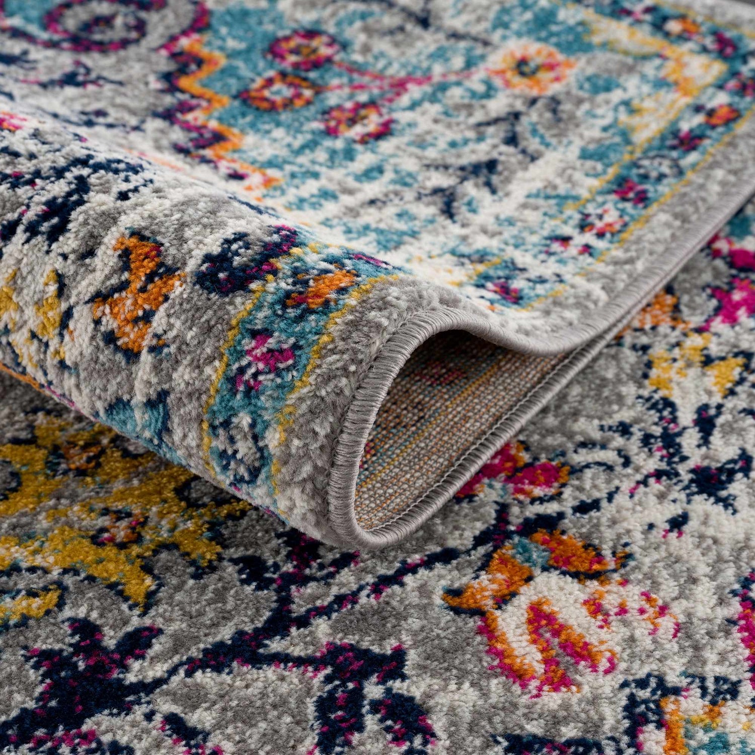 Close-up of the New Delanson Area Rug featuring a gray, floral pattern with accents of blue, pink, and yellow. Fold