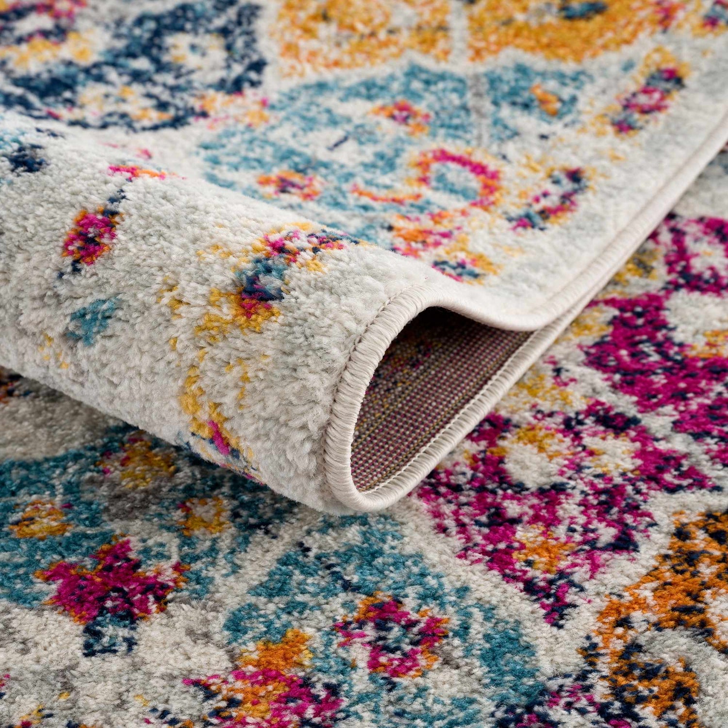 Close-up of the New Custar Area Rug. Farmhouse style rug in burgundy, burnt orange, charcoal, mustard, navy, peach, and teal. Fold
