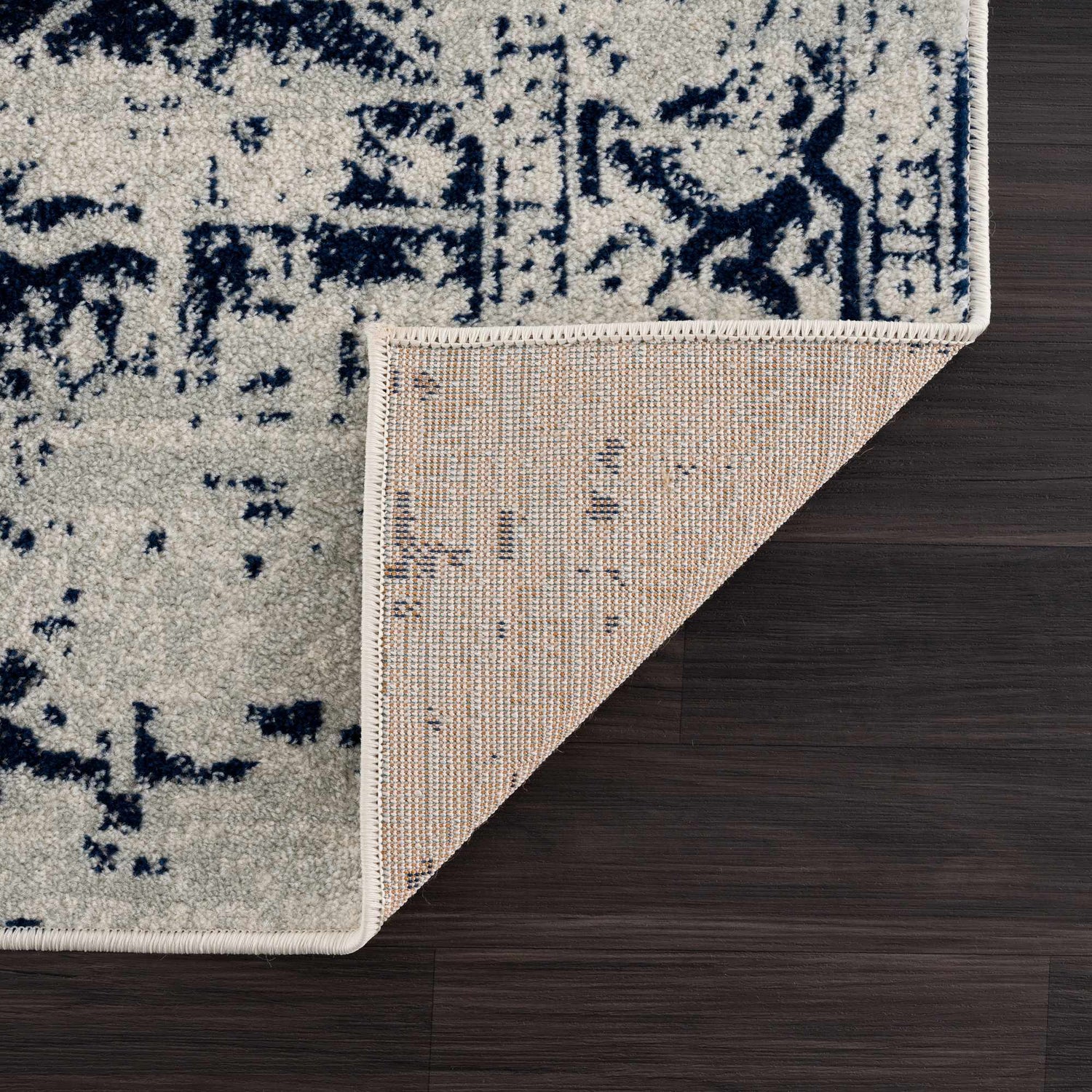 Close-up of New Limestone Area Rug showing medium gray and navy traditional pattern and rug backing. Fold