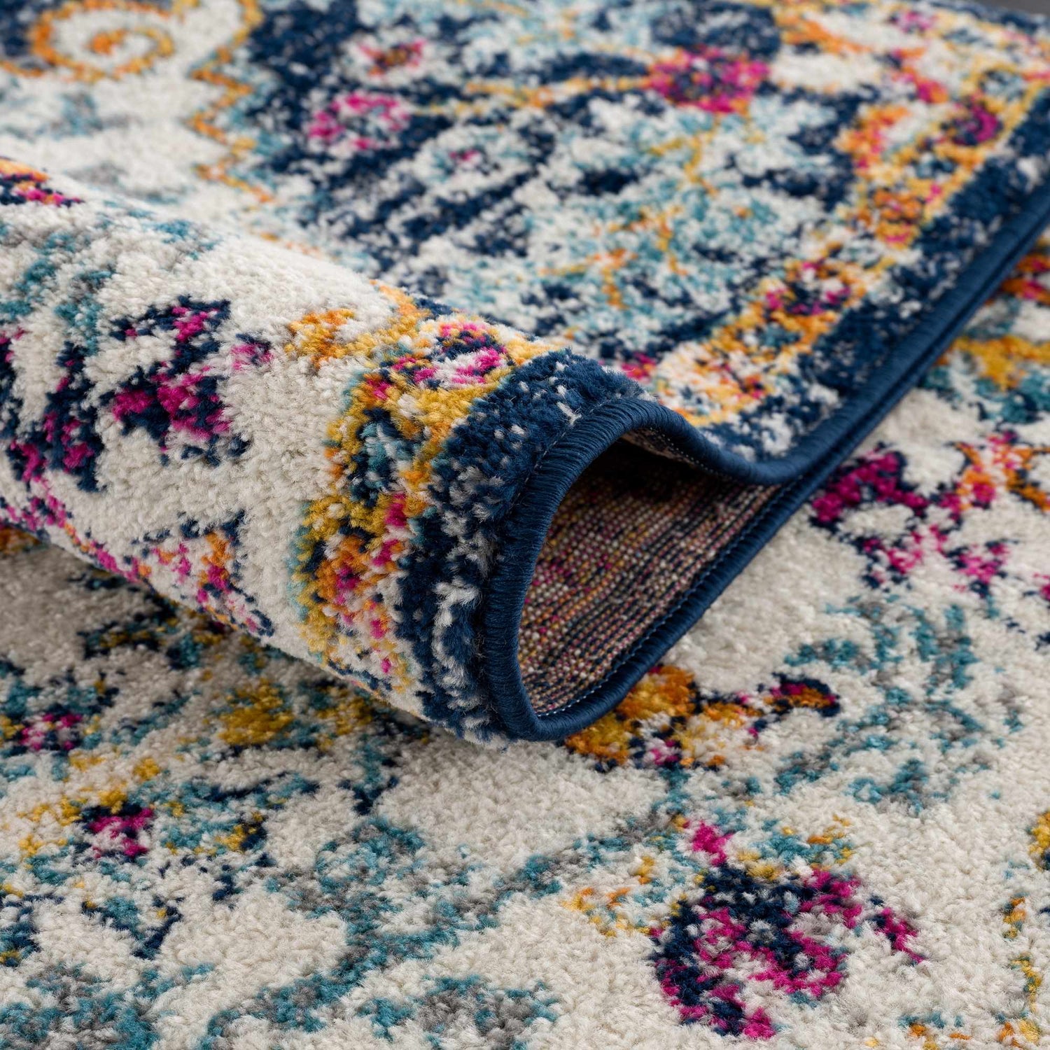 Close-up of the Bodrum Lite Colorful Rug showing its floral pattern, plush texture, and colors: blue, pink, and yellow. Fold