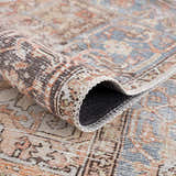 Close-up of the Eira Distressed Washable Rug showing its charcoal, blue, orange, and off-white Persian-style pattern and texture. Fold