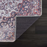 Close-up of the Red Cael Tumble Dry Washable Rug showing its oriental pattern, red, blue, and off-white colors, and non-slip backing. Fold