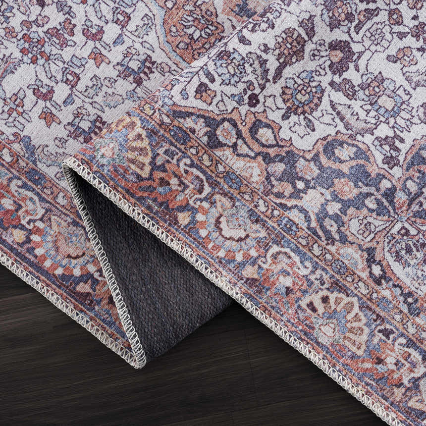 Close-up of the Red Cael Tumble Dry Washable Rug, showcasing its vintage Persian pattern and colors: red, blue, and off-white. Fold