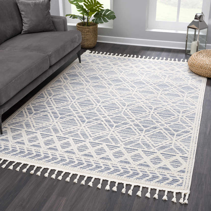Living room scene with gray sofa and Magnolia Blue 2302 Area Rug. The rug has a cream and blue geometric pattern with tassels. Roomscene-Rectangle