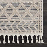 Close-up of Magnolia Cream 2300 Area Rug showing geometric pattern, soft texture, and braided fringe detail. Beige, cream, and smoke colors. Swatch