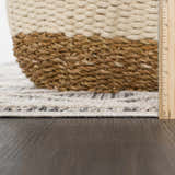 Close-up of Magnolia Cream 2300 rug pile height, showing beige and gray geometric pattern and texture next to a woven basket. Pile