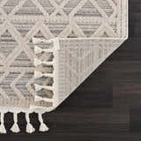 Close-up of Magnolia Beige 2301 rug showing geometric pattern, beige tones, tassels, and durable polypropylene construction. Fold
