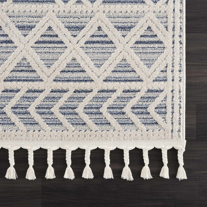 Close-up of the Magnolia Blue 2302 Area Rug, featuring a geometric pattern in cream and dark blue with braided tassels. Swatch