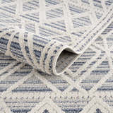 Close-up of the Magnolia Blue 2302 Area Rug showing cream and dark blue geometric pattern and soft, textured polypropylene pile. Fold