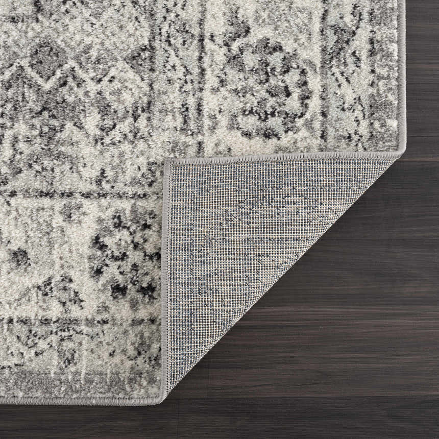 Close-up of the Marash KMRSH-4615 area rug showing its black, gray, and ivory bohemian pattern and machine-made construction. Fold
