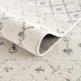 Close-up of the Marash KMRSH-4606 area rug showing the cream color and gray geometric pattern. Machine-made polypropylene texture. Fold