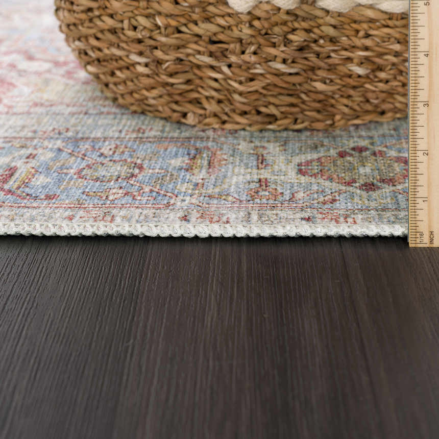 Close-up of the Cream Rust Leeston Washable Rug showing its brick red, light blue, and cream vintage pattern and texture. Pile
