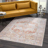 Living room scene with a Rust Maayon Washable Rug, mustard sofa, dark wood floors, and silver lanterns. Roomscene-Rectangle