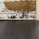 Close-up of the Bayanga rug showing its shag texture, charcoal and white pattern, and a basket on top. Pile