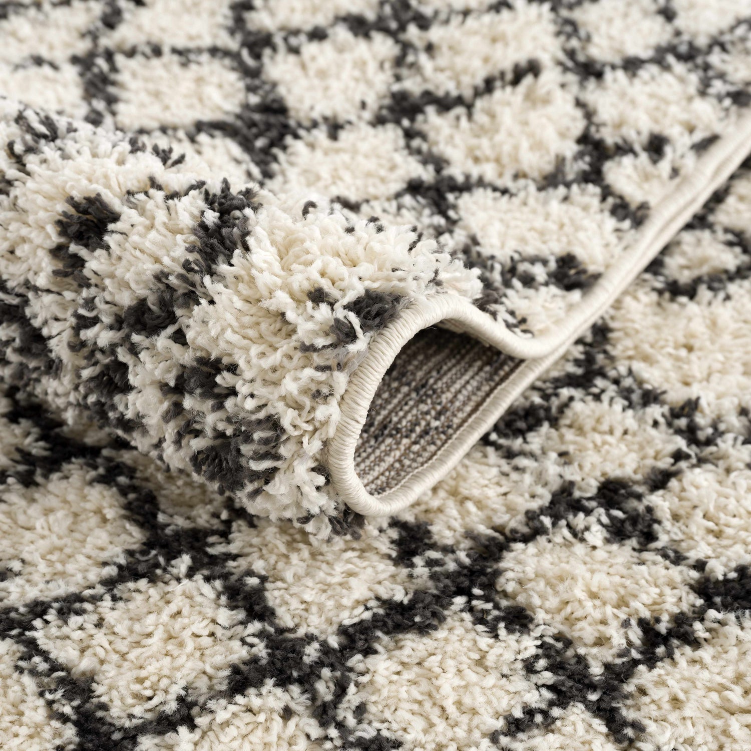 Close-up of the Muni Berber Shag Rug. Charcoal and light beige shag rug with a geometric Moroccan-inspired pattern. Fold