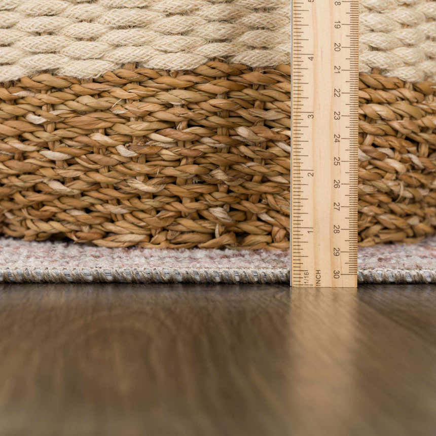 Close-up of Niran area rug showing detail of the rug's edge, texture, and pile height with a ruler for scale. Pile
