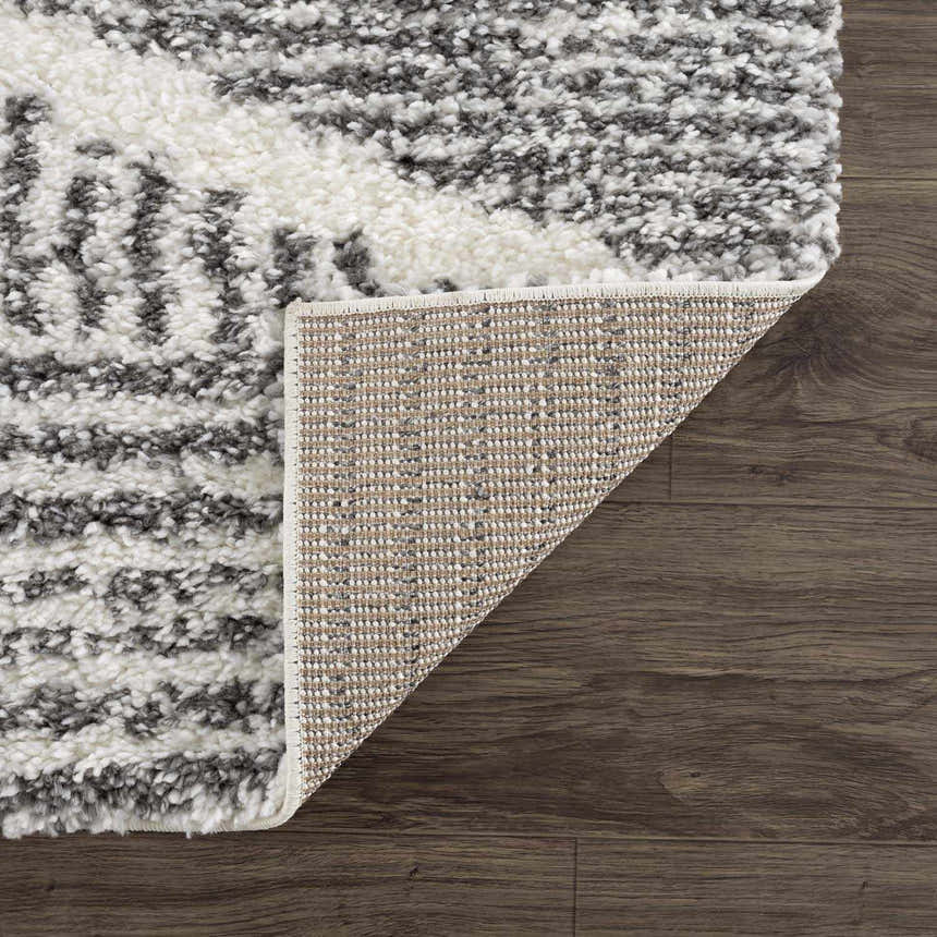 Close-up of the Trunding Plush Area Rug showing its charcoal and cream shag texture and woven backing. Fold