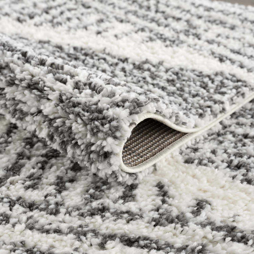 Close-up of the Trunding Plush Area Rug. Charcoal and cream shag rug with a plush, textured feel. Fold