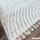Close-up of the Dauin 3D Rainbow Area Rug showing the gray and cream geometric pattern and tassel fringe detail. Roomscene-Rectangle