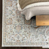 Bedroom scene with Dion Washable Floral Rug in charcoal, beige, and blue. Farmhouse style with bed and wooden bench. Roomscene-Rectangle