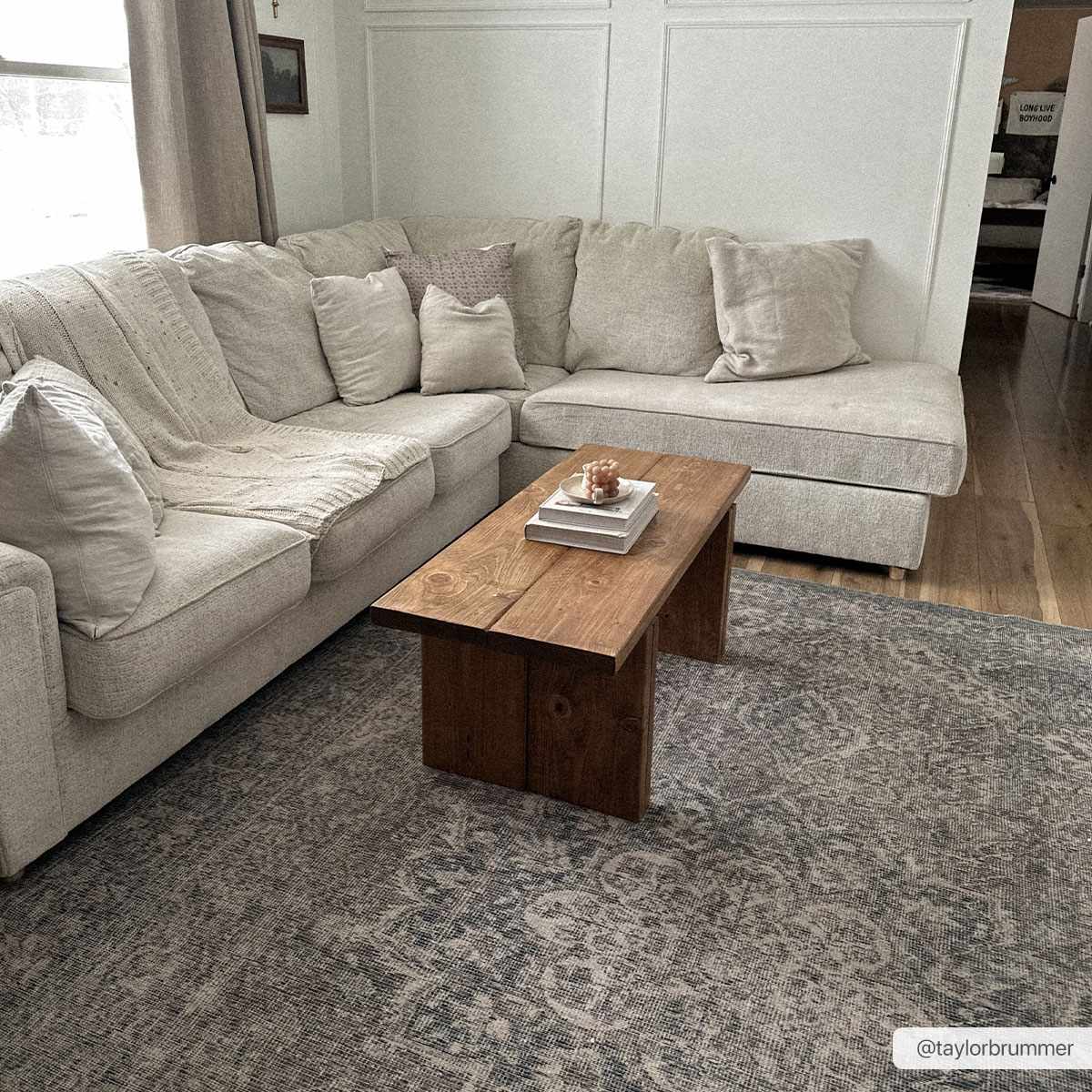 Living room scene with a Greenpoint Dusty Blue Washable Rug under a rustic wood coffee table and beige sectional sofa. Roomscene-Rectangle