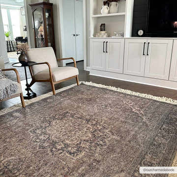 Living room scene with a Greenpoint Dusty Blue Washable Rug, neutral armchairs, and white built-in shelving. Roomscene-Rectangle