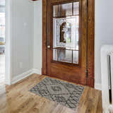Entryway with a Marwood Nordic Performance Rug in black, charcoal, taupe, and white by a wood door and radiator. Roomscene-Rectangle