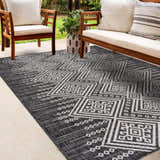 Outdoor patio scene with wood furniture and a Frankville Black&White All Over Performance Rug with a geometric pattern. Roomscene-Rectangle