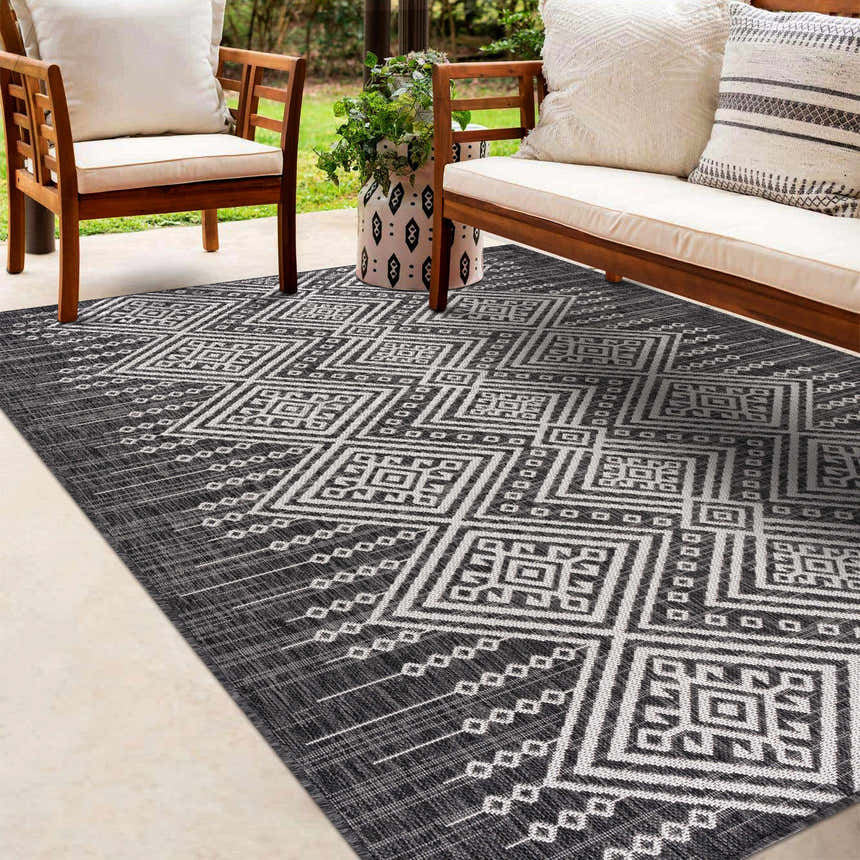 Outdoor patio scene with wood furniture and a Frankville Black&White All Over Performance Rug with a geometric pattern. Roomscene-Rectangle