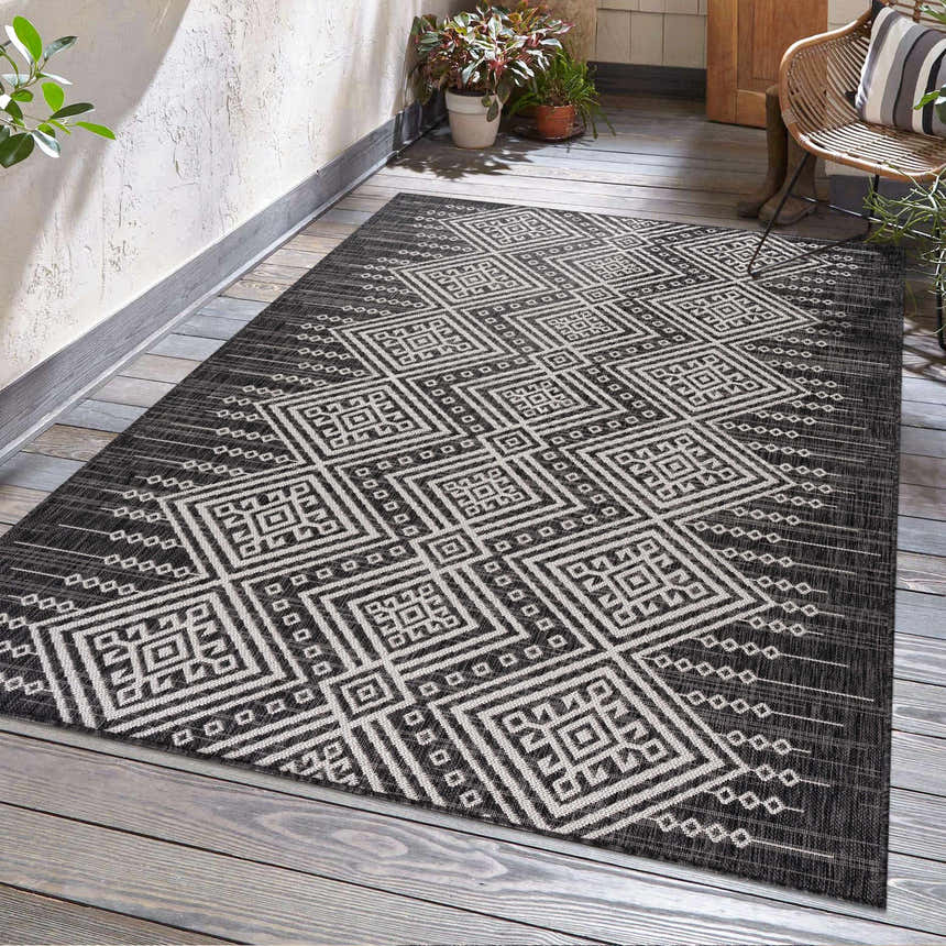 Outdoor patio scene with a Frankville Black&White All Over Performance Rug, wicker chair, and plants. Roomscene-Rectangle