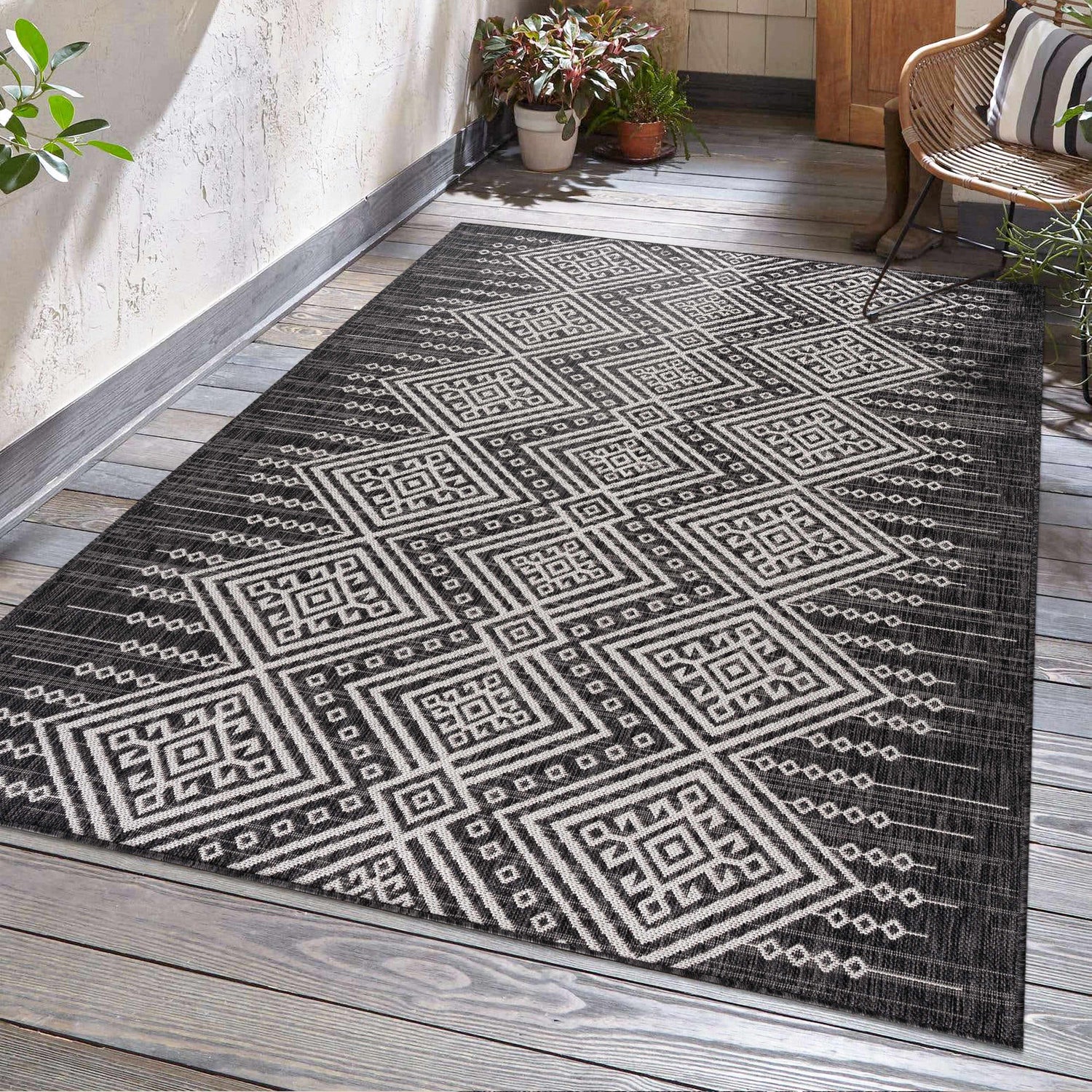 Outdoor patio scene with a Frankville Black&White All Over Performance Rug, wicker chair, and plants. Roomscene-Rectangle