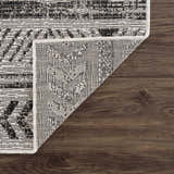 Close-up of the Catrine Indoor & Outdoor Rug showing the black, charcoal, and off-white bohemian pattern and machine-woven texture. Fold