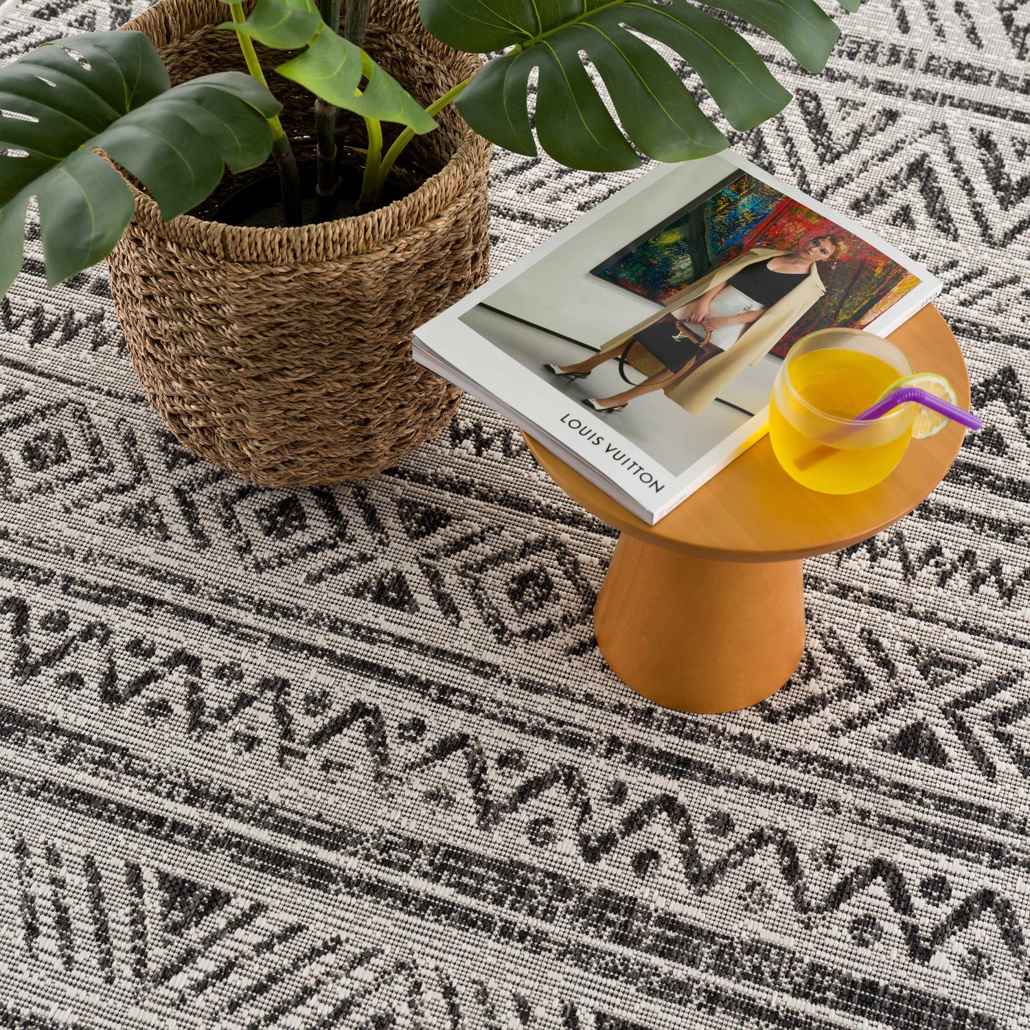 Close-up of the Catrine Indoor & Outdoor Rug showing its black, charcoal, and off-white bohemian pattern and woven texture. Styleshot