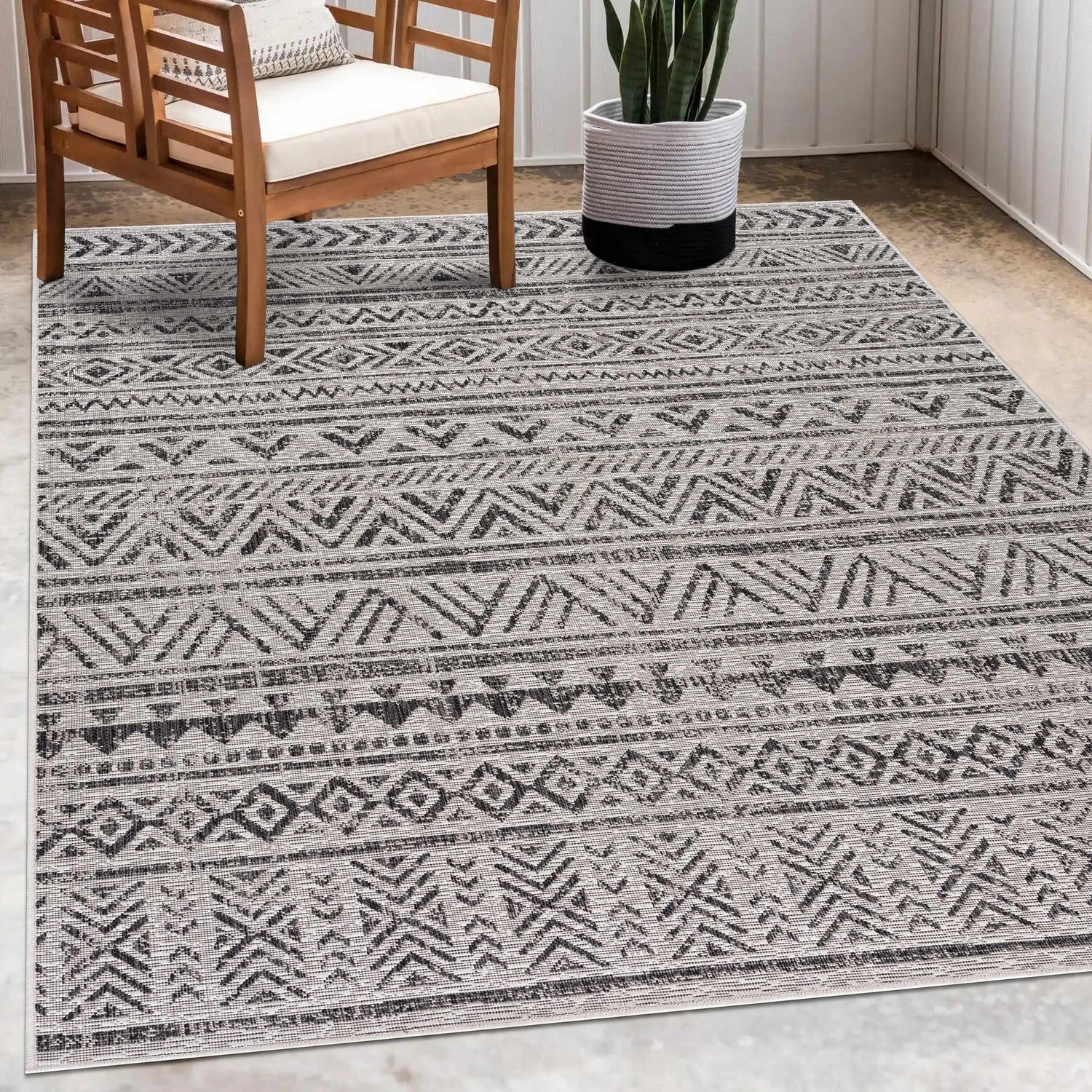 Patio scene with a Catrine Indoor Outdoor Rug in black, charcoal, and off-white with a bohemian design. Roomscene-Rectangle