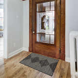 Entryway scene with a Stephan Area Rug in black, charcoal, cream, and light gray colors, wooden door with glass, and hardwood floor. Roomscene-Rectangle