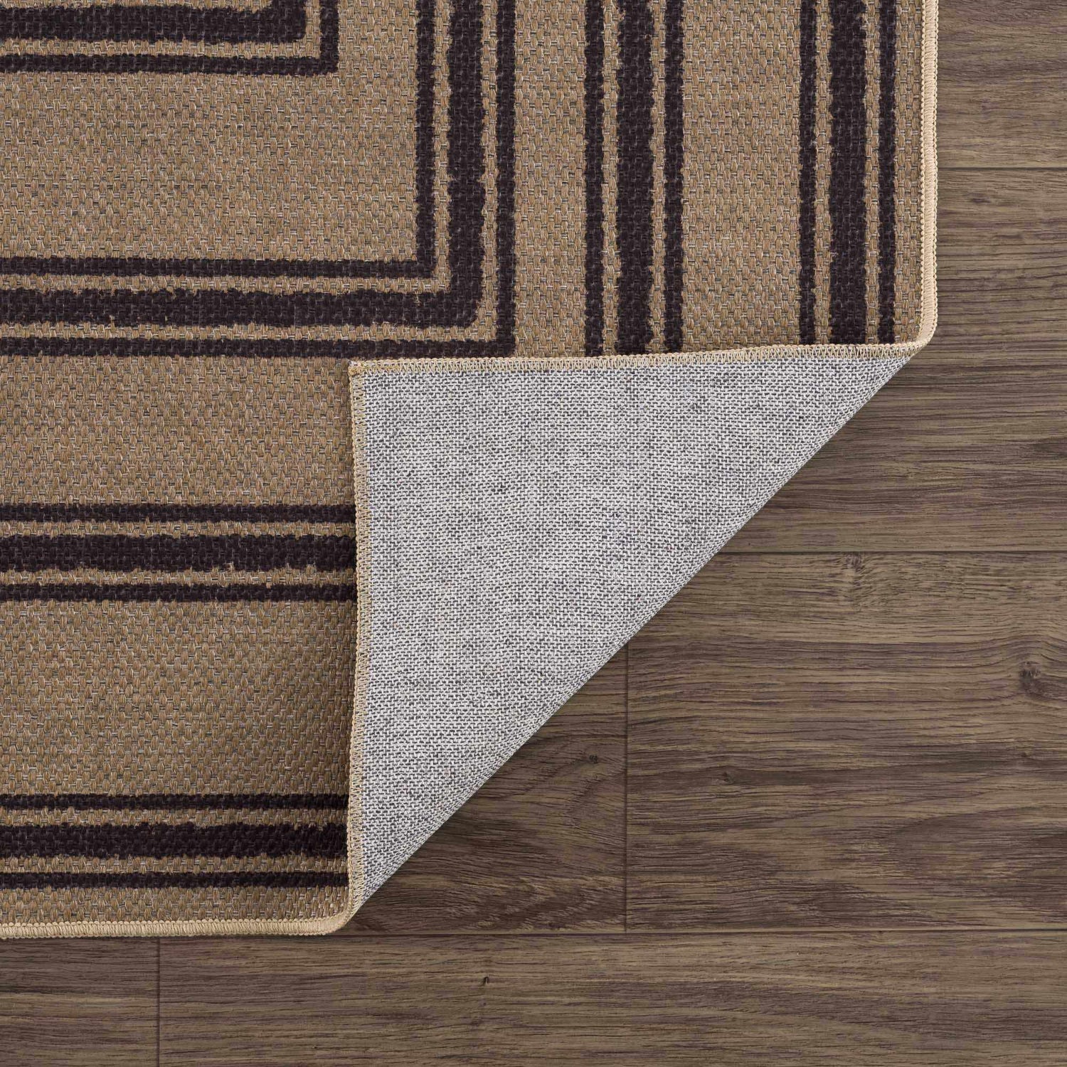 Close up of Coty Washable Jutely Rug showing brown jute texture and charcoal stripes on dark wood floor. Fold
