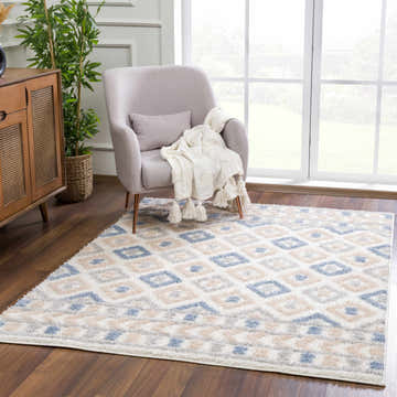 Living room scene with Eivin Pink & Blue Area Rug, gray armchair, wood cabinet, and indoor plant near a window. Roomscene-Rectangle