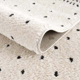 Close up of the Julie Area Rug showing its beige, fluffy texture and black polka dot geometric pattern. Fold